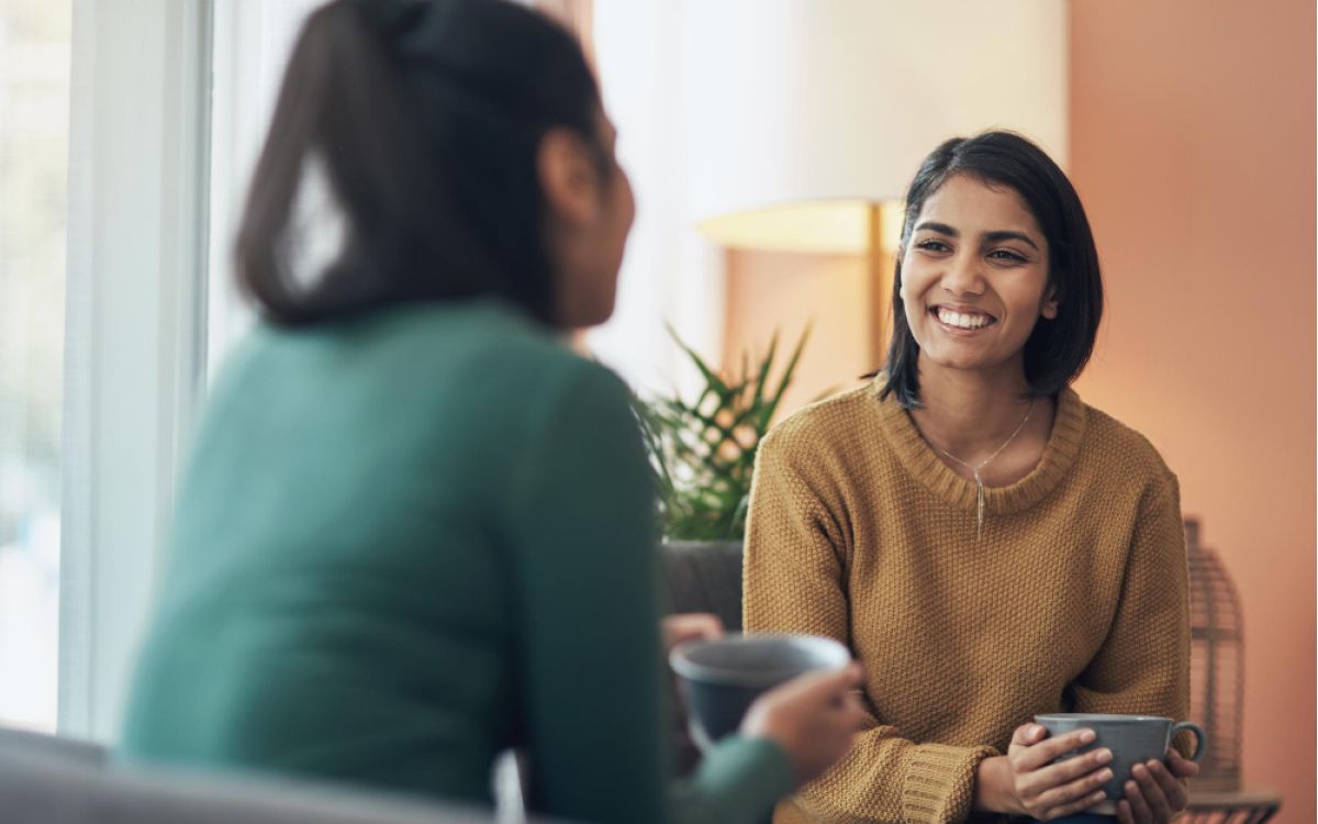 Two women in a conversation holding tea mugs